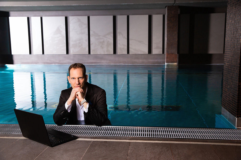 Christian Tröger im Anzug im Schwimmbecken mit Laptop